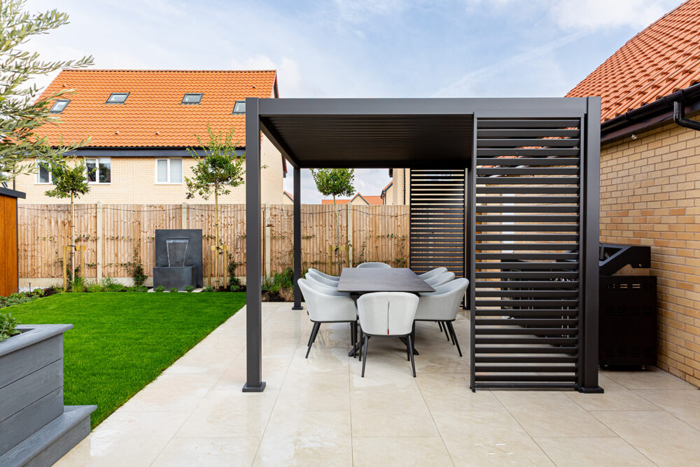 Louvered pergola over outdoor kitchen with porcelain worktops and built-in storage